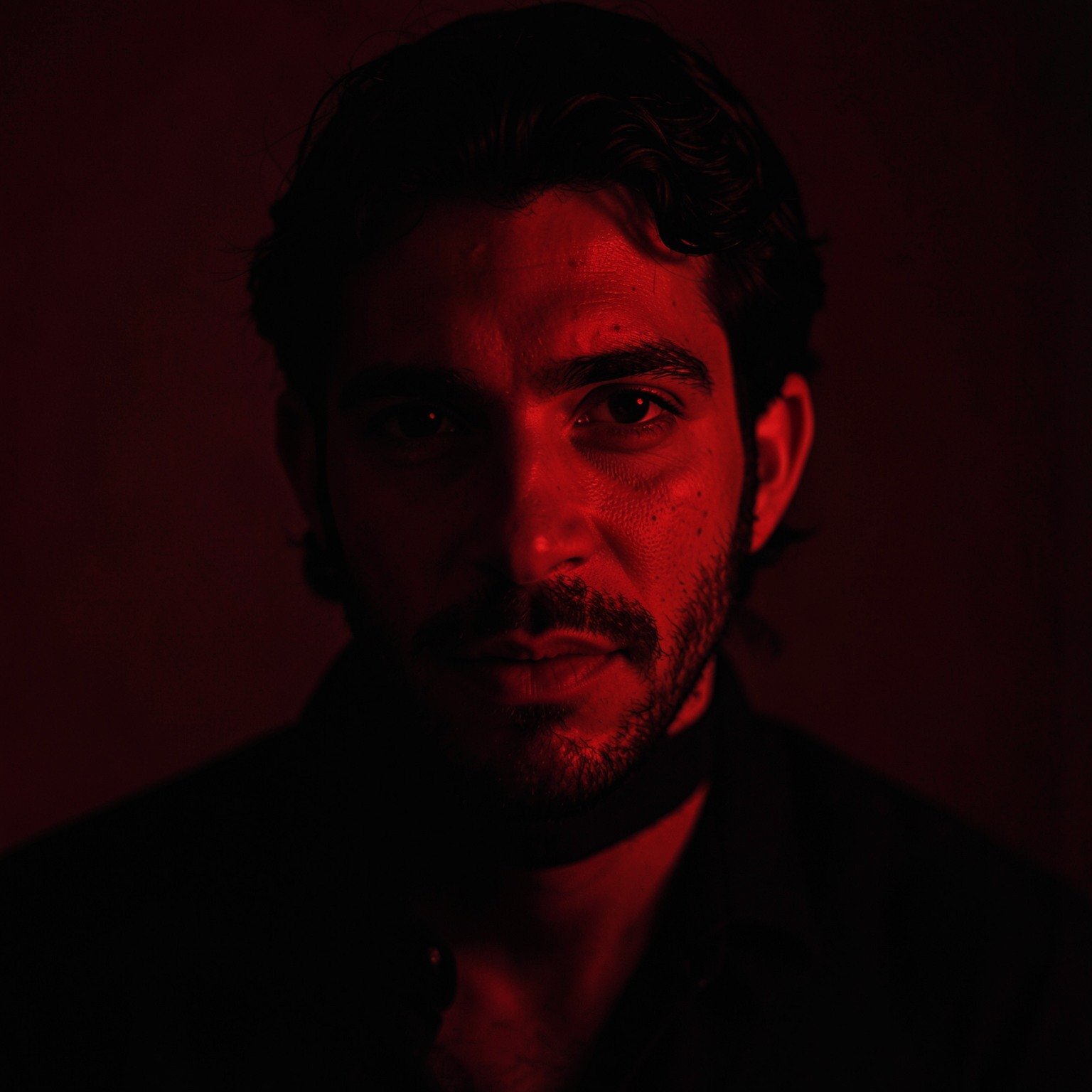 Moody portrait with dark red lighting and mysterious expression