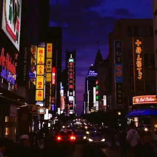 A lively cityscape at twilight, with bustling streets illuminated by the glow of neon lights, capturing the vibrancy and energy of urban life.